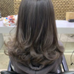 毛先に細く明るい色が入った暗髪のロングヘアーの女性